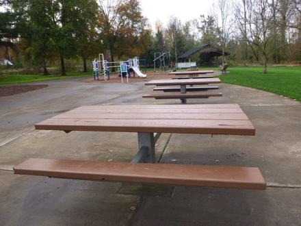 Hard surface path and under picnic tables – playground - splash pad – benches – covered shelter – lawn